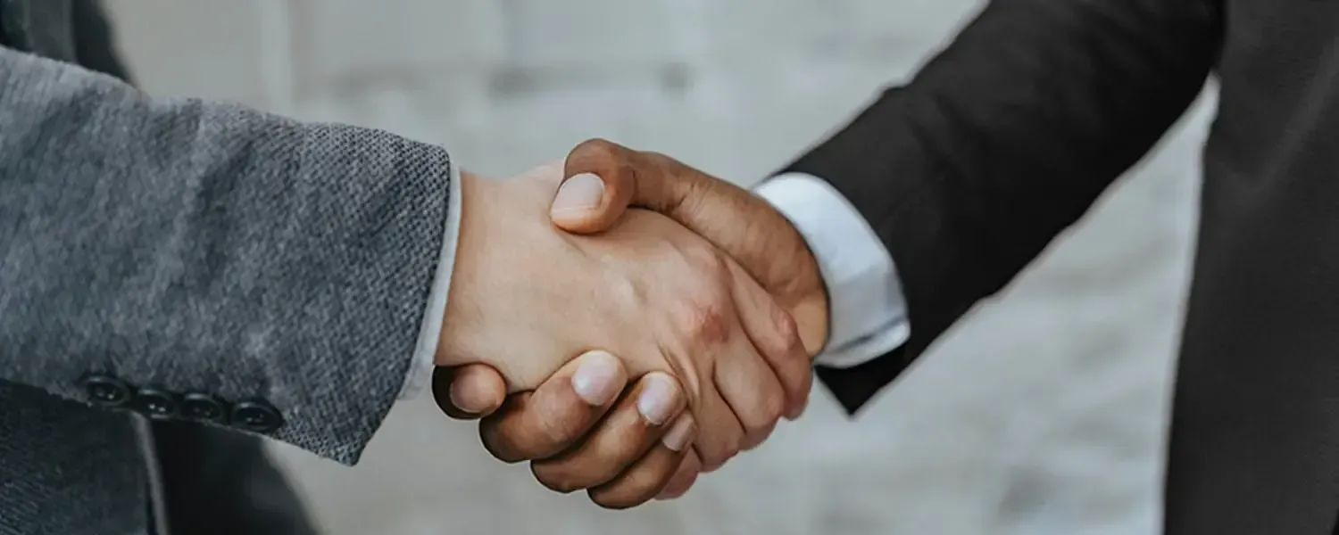 Two people in suits shaking hands.